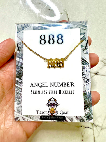 A hand holding a packaged gold-tone stainless steel 888 number necklace with a rectangular 'angel number' pendant. The necklace is displayed on a white card labeled '888' and 'Angel Number Stainless Steel Necklace' with the brand name 'Tarot Goat' at the bottom.