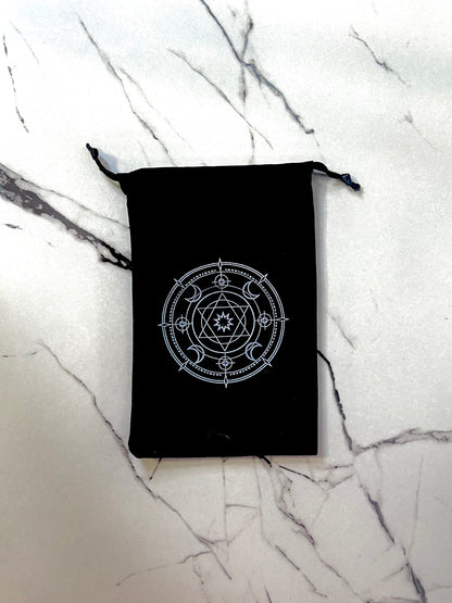 Black drawstring bag with a star witchy symbol for energy protection on a marble surface 