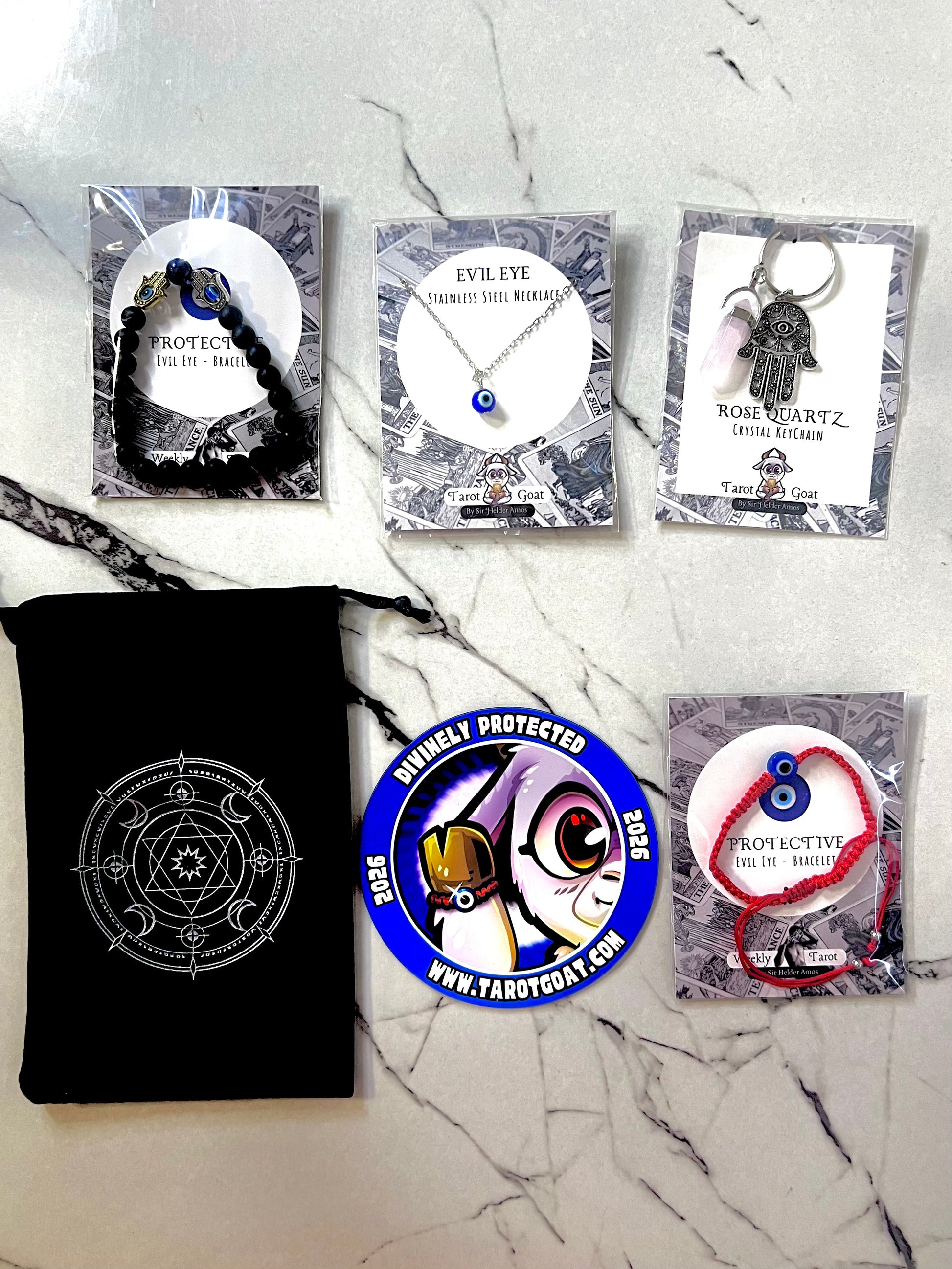Collection of protective evil eye amulets and charms such as nazar bracelet, crystal keychain, Turkish eye necklace, special limited edition magnet, and velvet black pouch  packaging on a marble surface