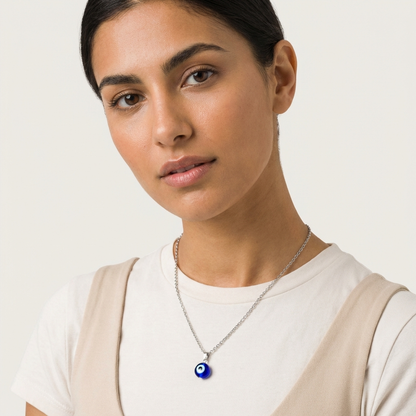 Woman wearing a necklace with an eye-shaped pendant on a plain background