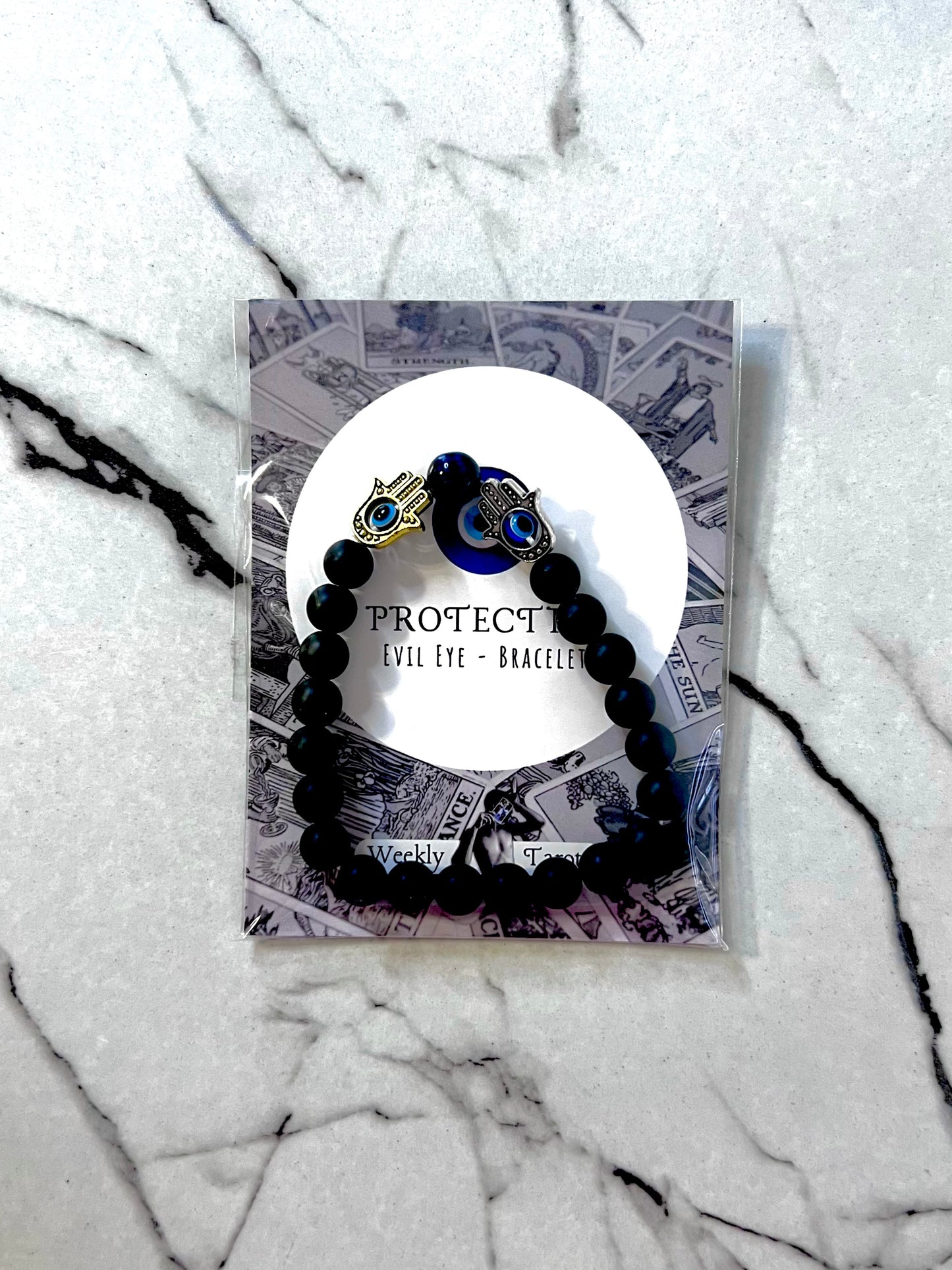 Black beaded bracelet for energy protection, displayed on a marble surface.