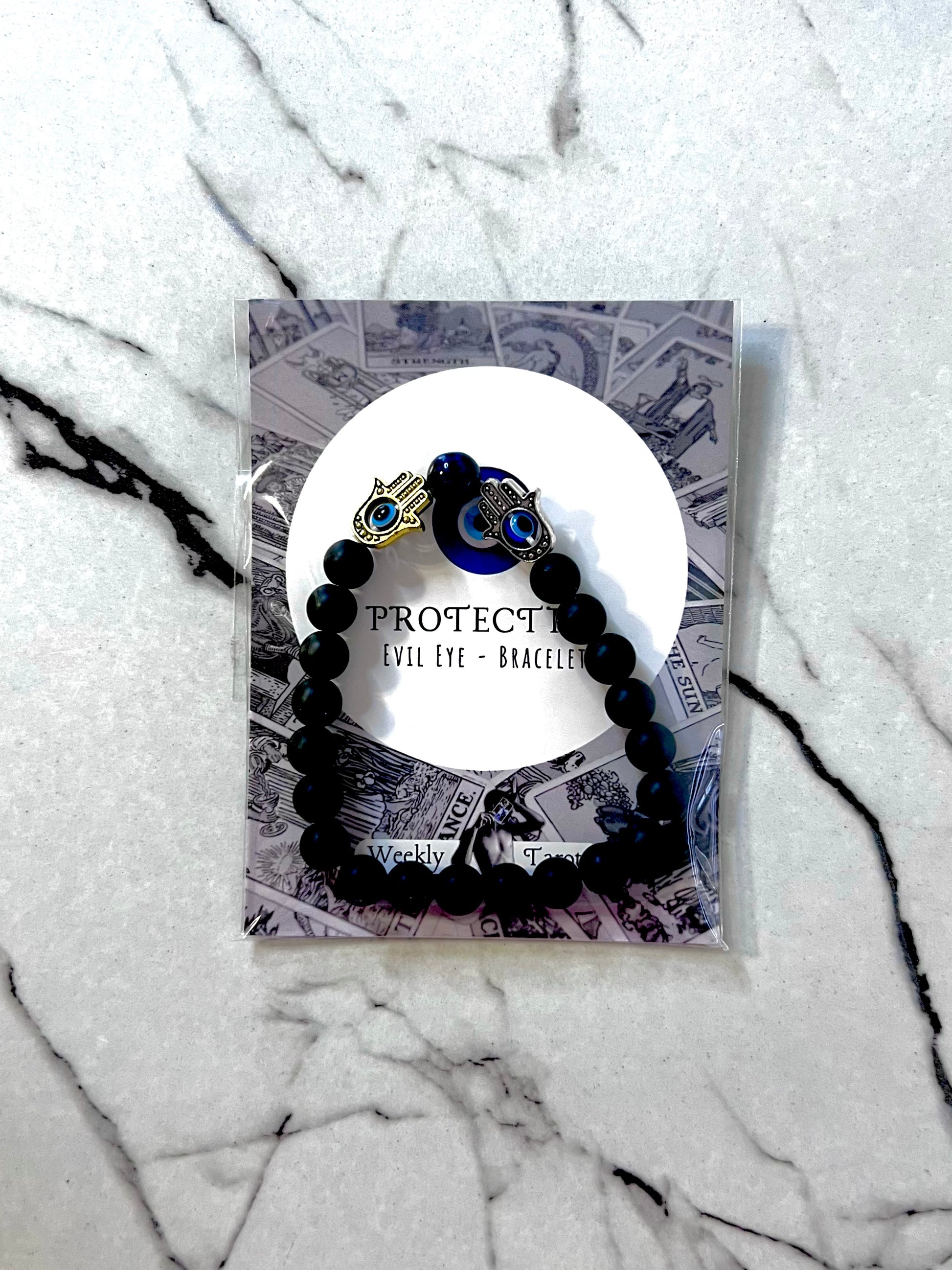 Black beaded bracelet for energy protection, displayed on a marble surface.