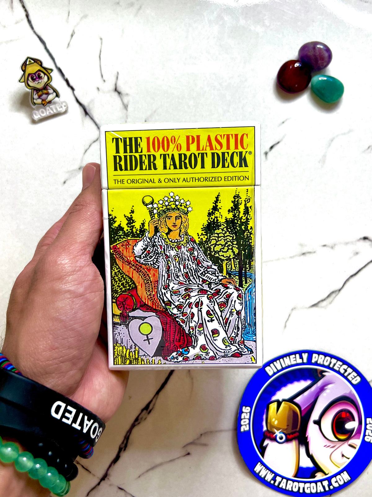 A hand with a goated bracelet, holding a tarot deck for beginners in an online shop