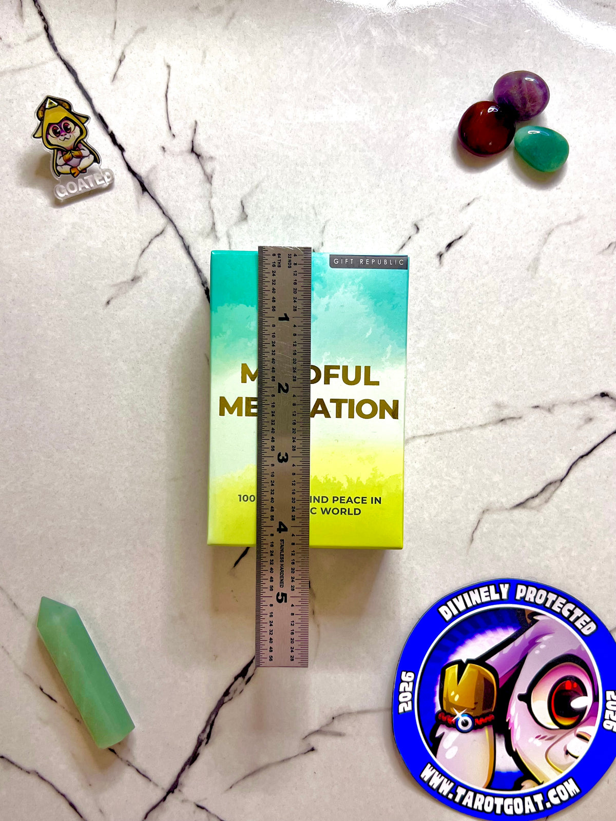 A set of 100 guided meditations card for beginners for sale on a marble table being measured by a ruler to display size. 
