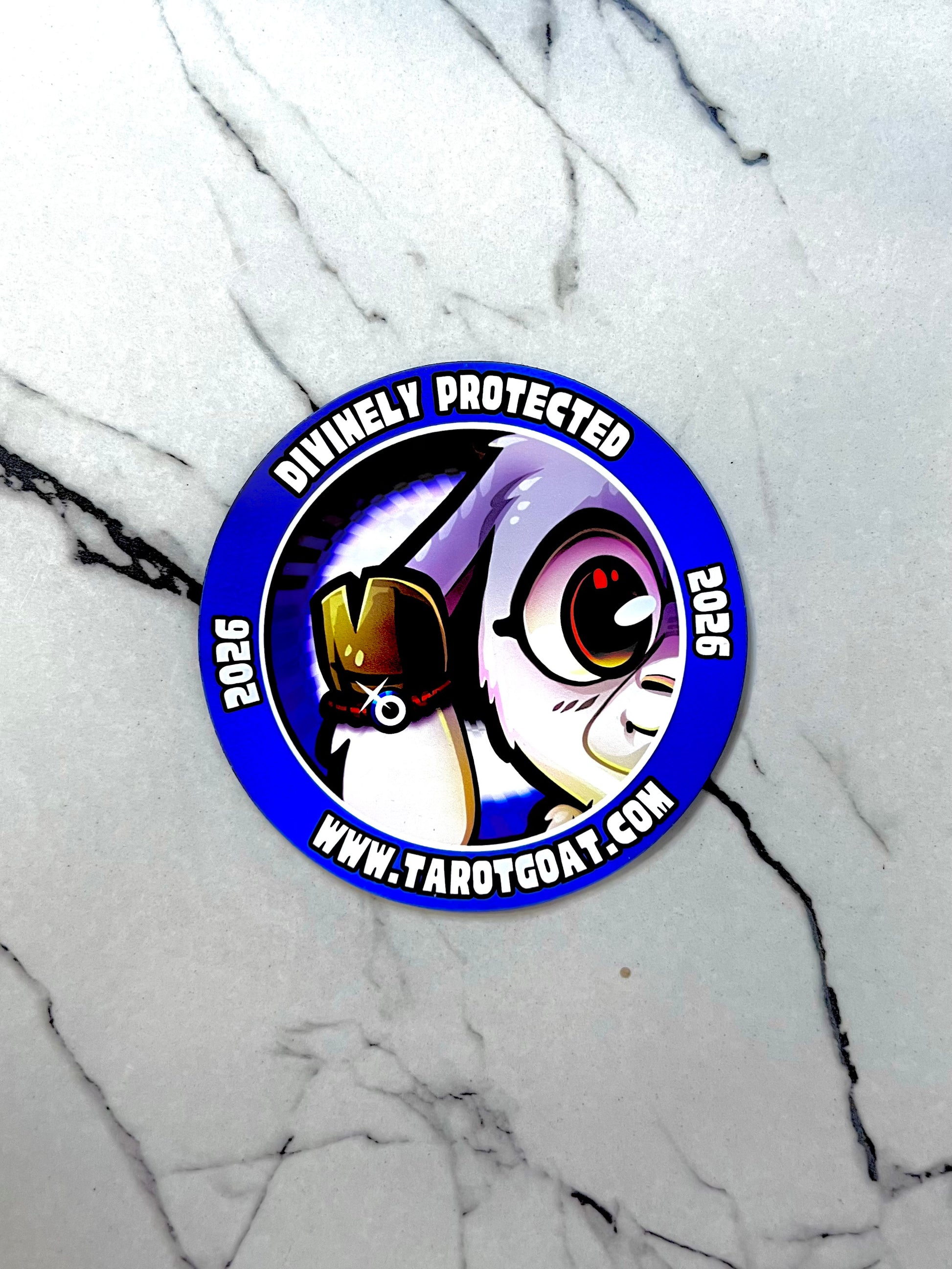 Circular car  fridge magnet  with Tarot Goat wearing a red evil eye protection bracelet and text 'Divinely Protected 2025' on a marble background