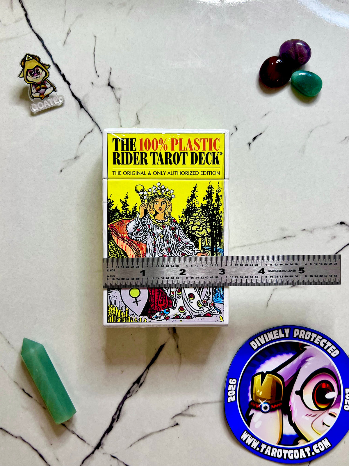  a 100% plastic tarot deck being measured by a ruler on a table with gems and tarot goat magnet